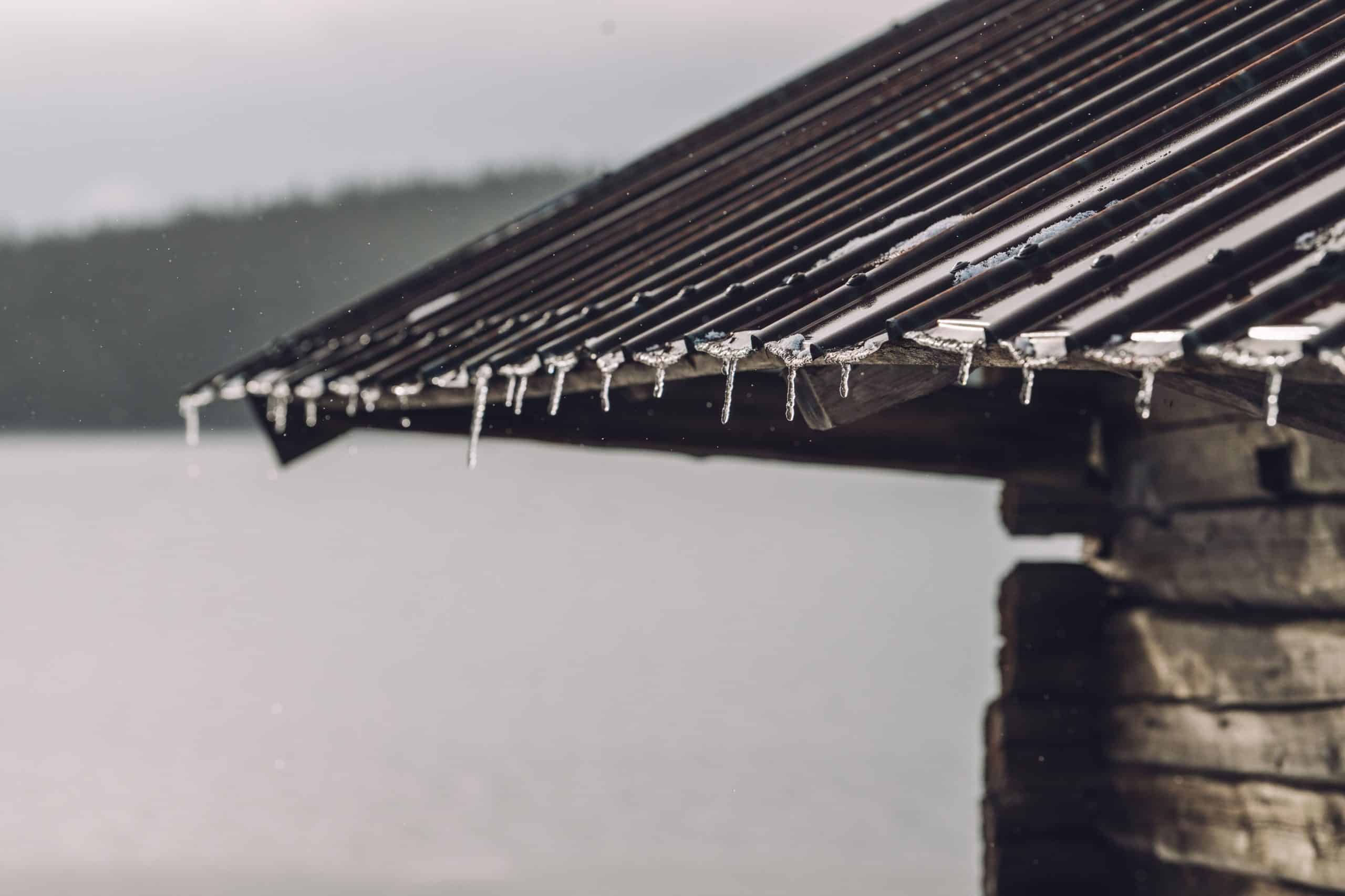 A selective focus of icicles and frost on a building roof with a blurry background